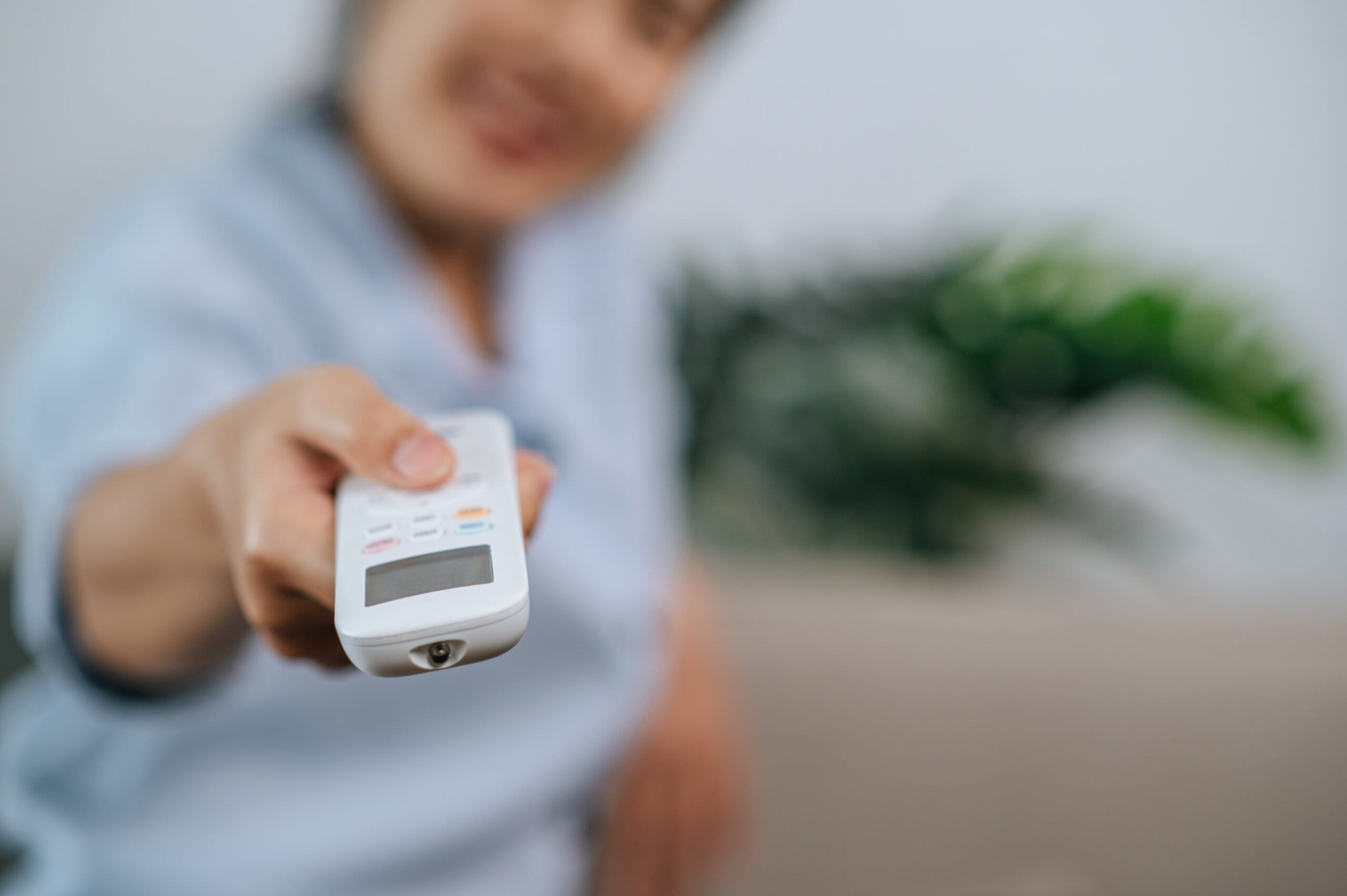 close up selective focus hand woman holding use remote control open aircondition living room home scaled